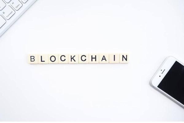 Un teclado y un celular en medio de un letrero de blockchain, tecnología en tendencia.