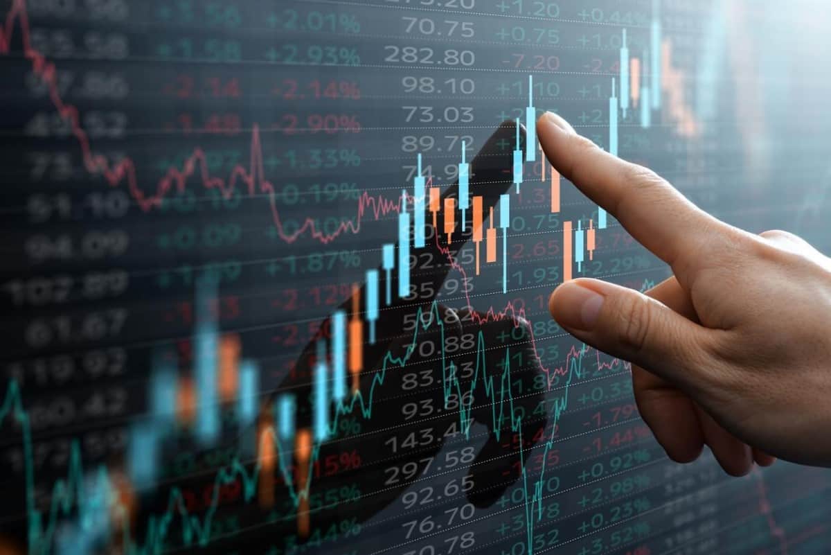 Un hombre revisa en una pantalla gráficos de velas de lo que es un activo financiero.