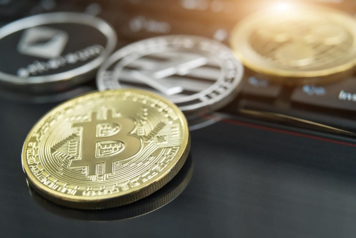 Bitcoin y otras cripto sobre una superficie oscura. Descubre en esta nota todo sobre la capitalización de criptomonedas.