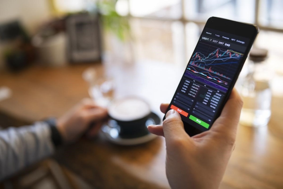 Trader analiza en su celular tendencias de criptomonedas en Colombia antes de comprar.