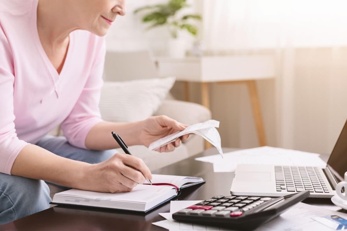 Una mujer revisa facturas y analiza sus gastos, lo que aprendió gracias a la educación financiera.