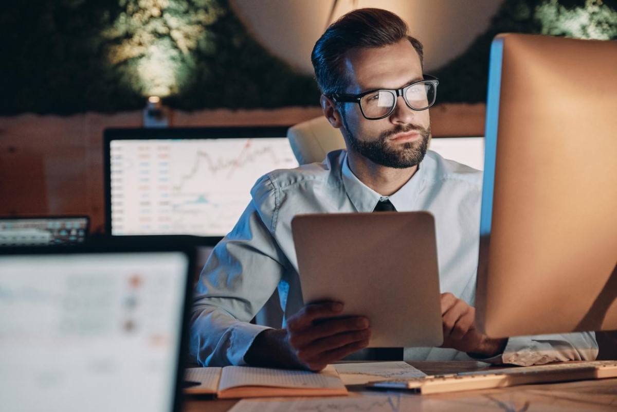 Un trader frente a su computadora y con una tablet consultando cotizaciones en Forex Chile.