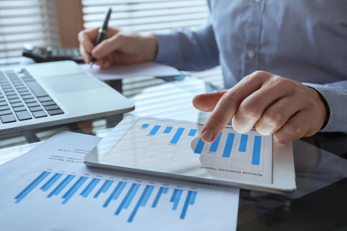 Un empresario analiza indicadores económicos y toma nota de ellos en un documento.