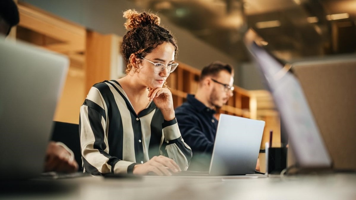 Una joven investiga en su laptop las ventajas de la inversión en tecnología.