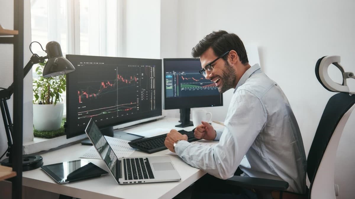 Trader sonríe frente a su laptop al ver el éxito de sus estrategias en el mercado Forex.