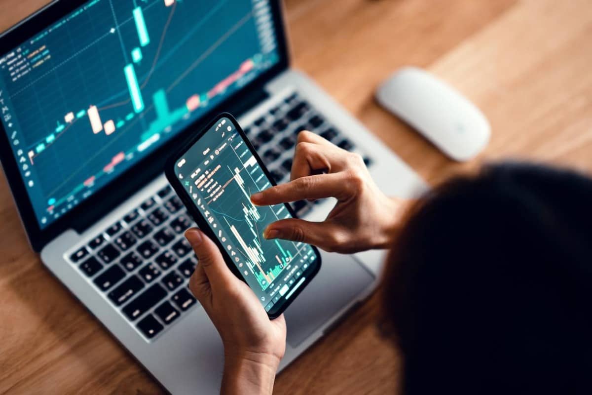 Una trader revisa en su celular gráficos de tendencias del mercado Forex.