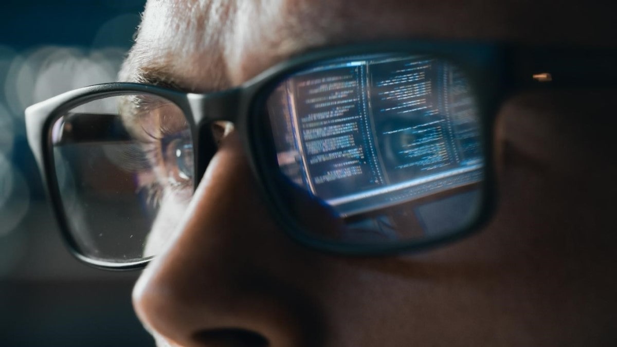 Joven analiza códigos en el computador mientras realiza minado de criptomonedas.