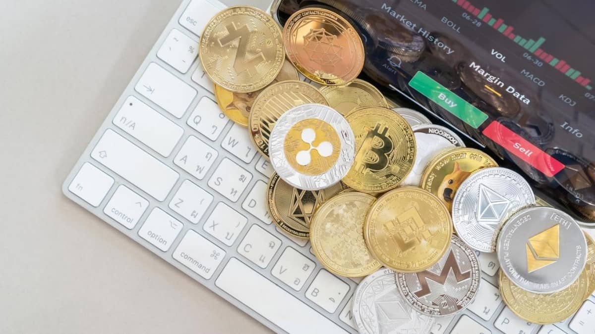 Varias crypto sobre un teclado y un gráfico del comportamiento del precio de criptomonedas.
