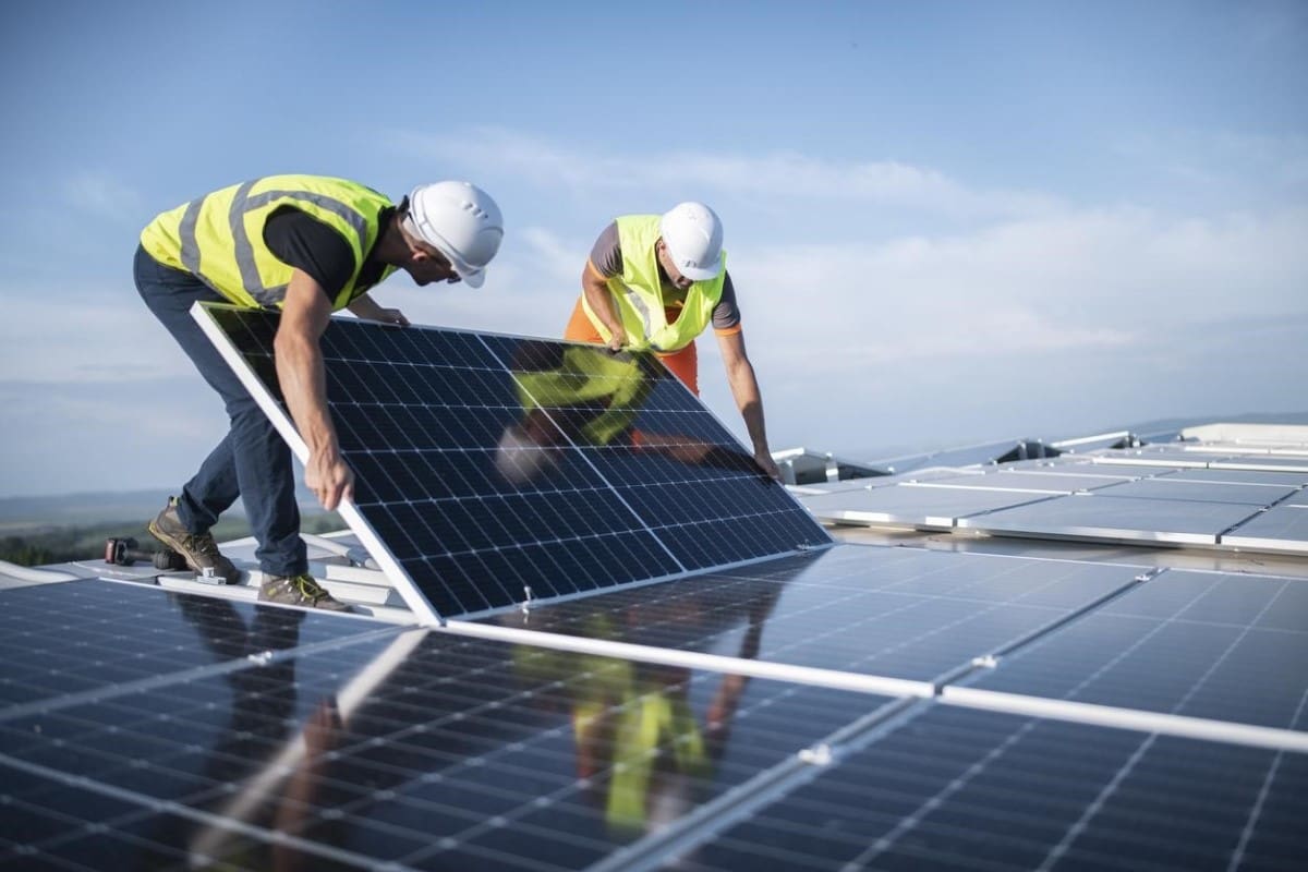 Dos hombres instalan paneles solares (destacada innovación de la tecnología verde).