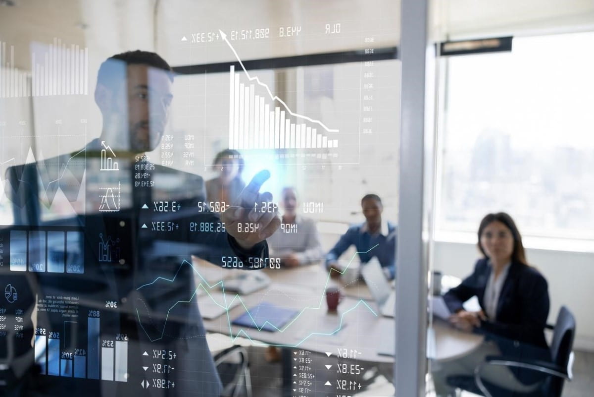 Equipo de empresarios analiza gráficos de diferentes tipos de acciones para invertir.